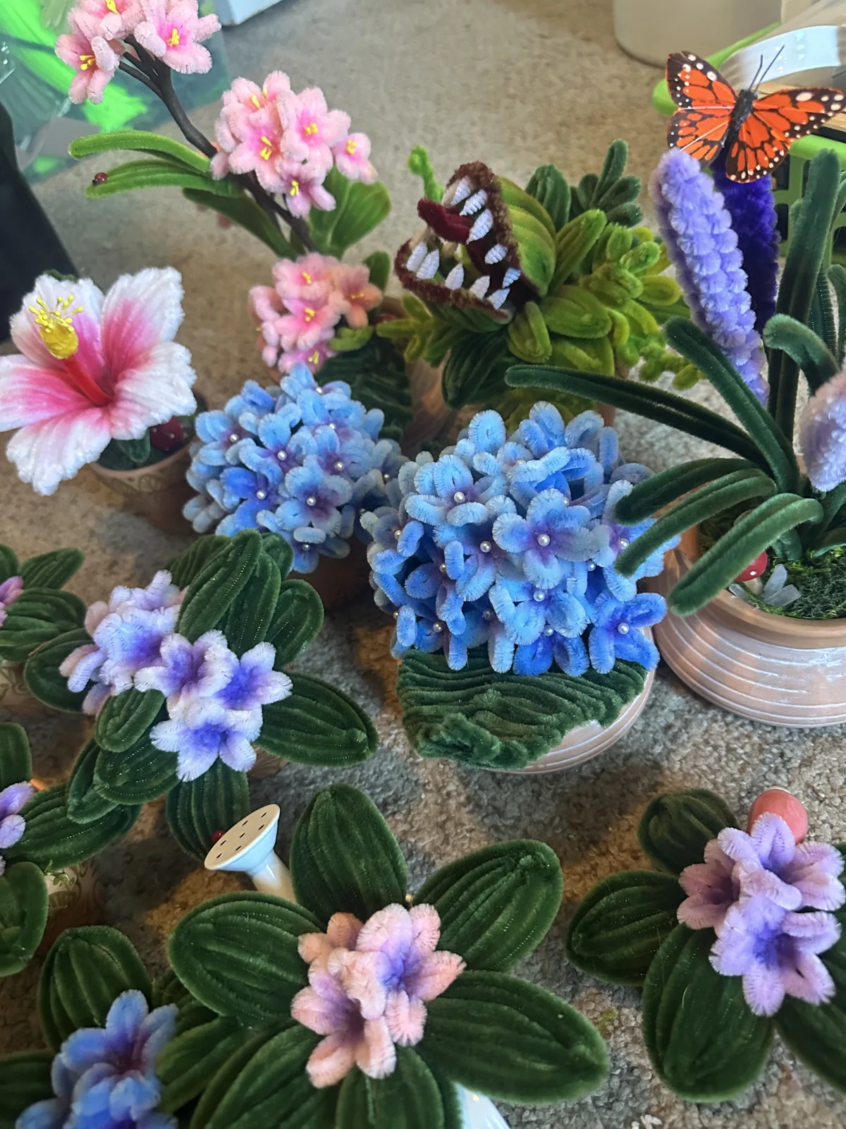 Blue, pink and purple wire hydrangeas and flowers with a monarch butterfly, laid out together